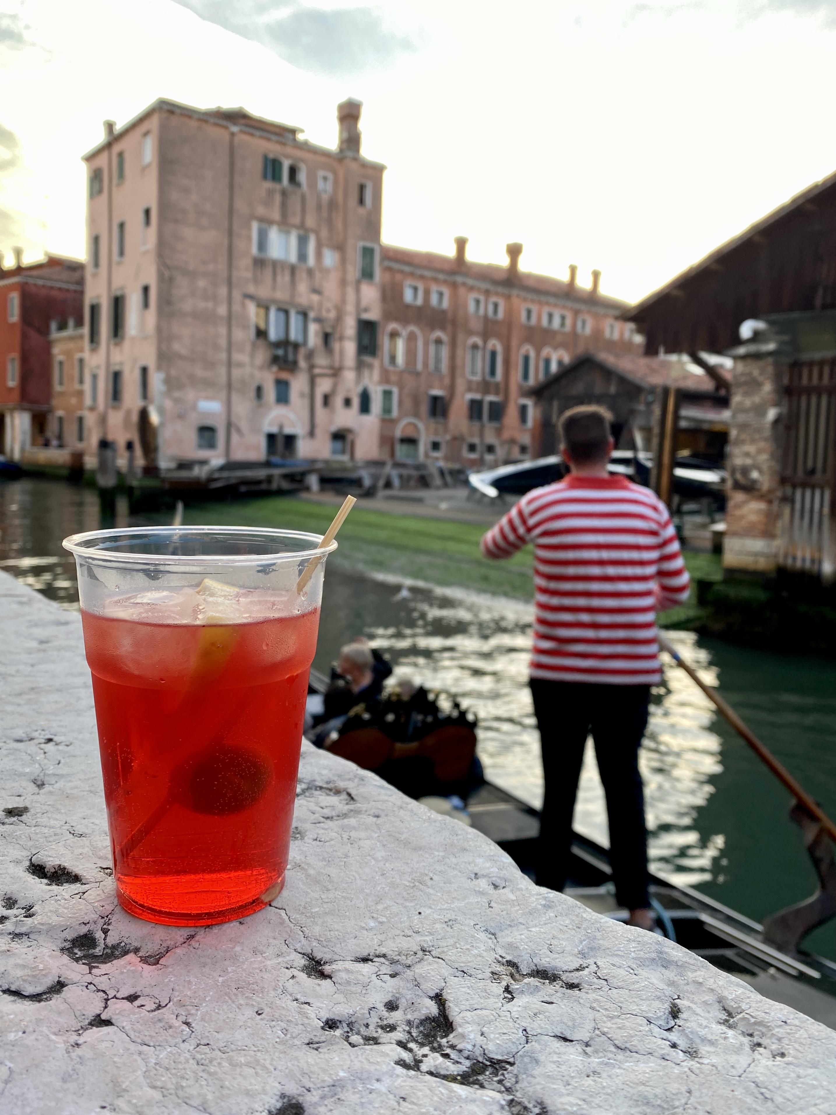 Italien, Venedig: Aperol Spritz auf der Mauer vor der Osteria Al Squero, im Hintergrund Gondoliere mit rot-weiß-geringeltem Shirt