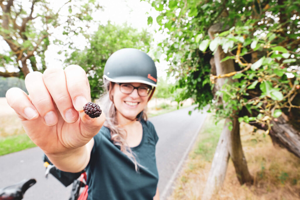 Maulbeerallee in Zernikow: Die Freundin von Wel mit Fahrradhelm zeigt eine Maulbeere