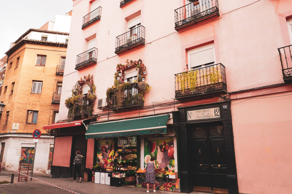 Straßenszene mit Gemüseladen und geschmückter Fassade in Madrid