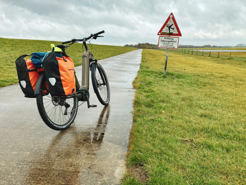 E-Bike neben Warnschild mit Flugzeug auf dem Nordseeküstenradweg