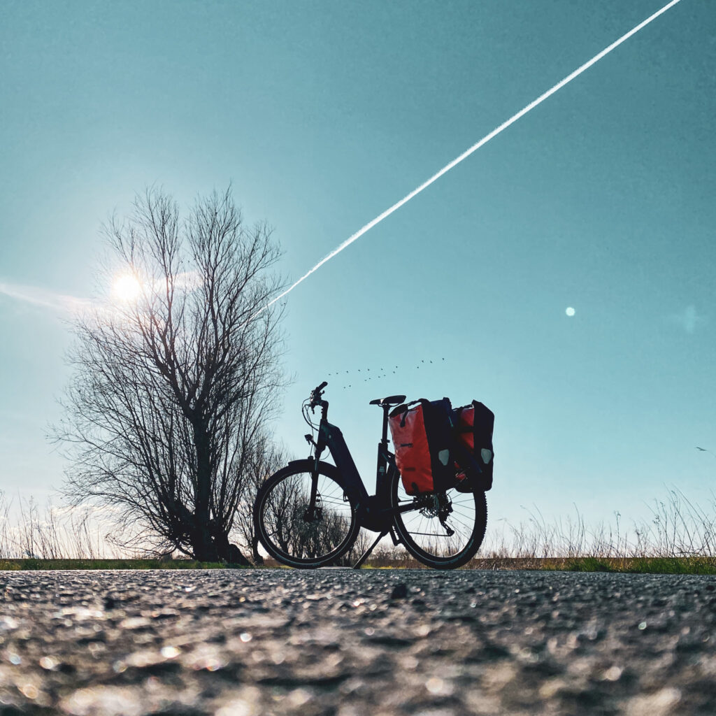 E-Bike mit Packtaschen im Gegenlicht auf dem Nordseekuestenradweg
