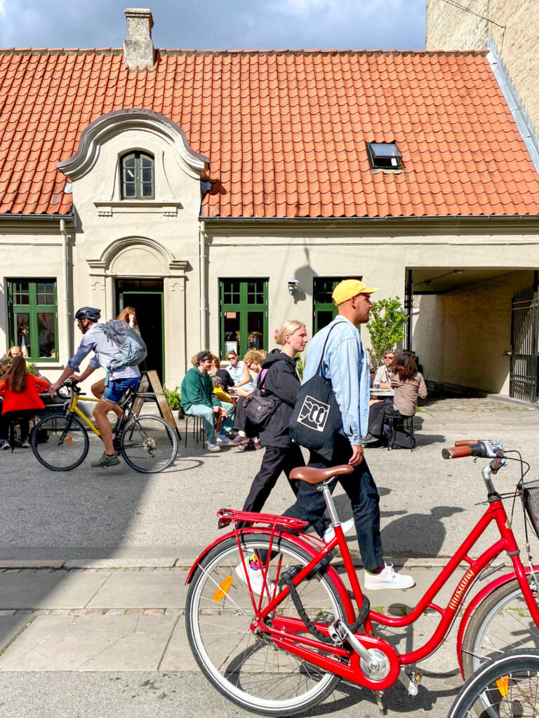 Das Café La Cabra in Aaarhus, davor Passanten und ein rotes Fahrrad