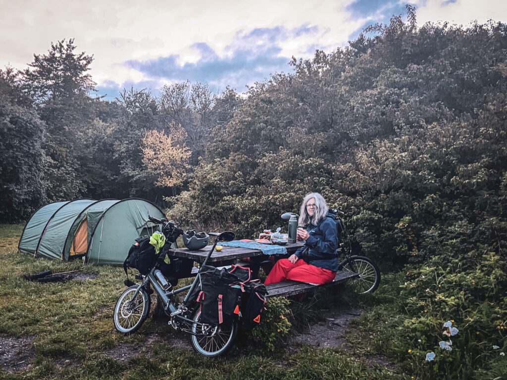 Camping in Dänemark, abends ein Tee am Picknicktisch vor dem Zelt