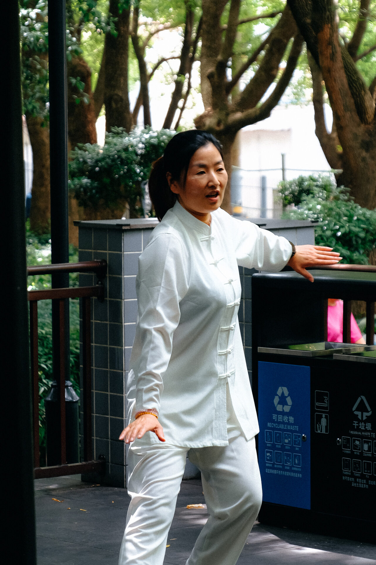 Frau im weißen Anzug macht Taijiquan im Park in Shanghai