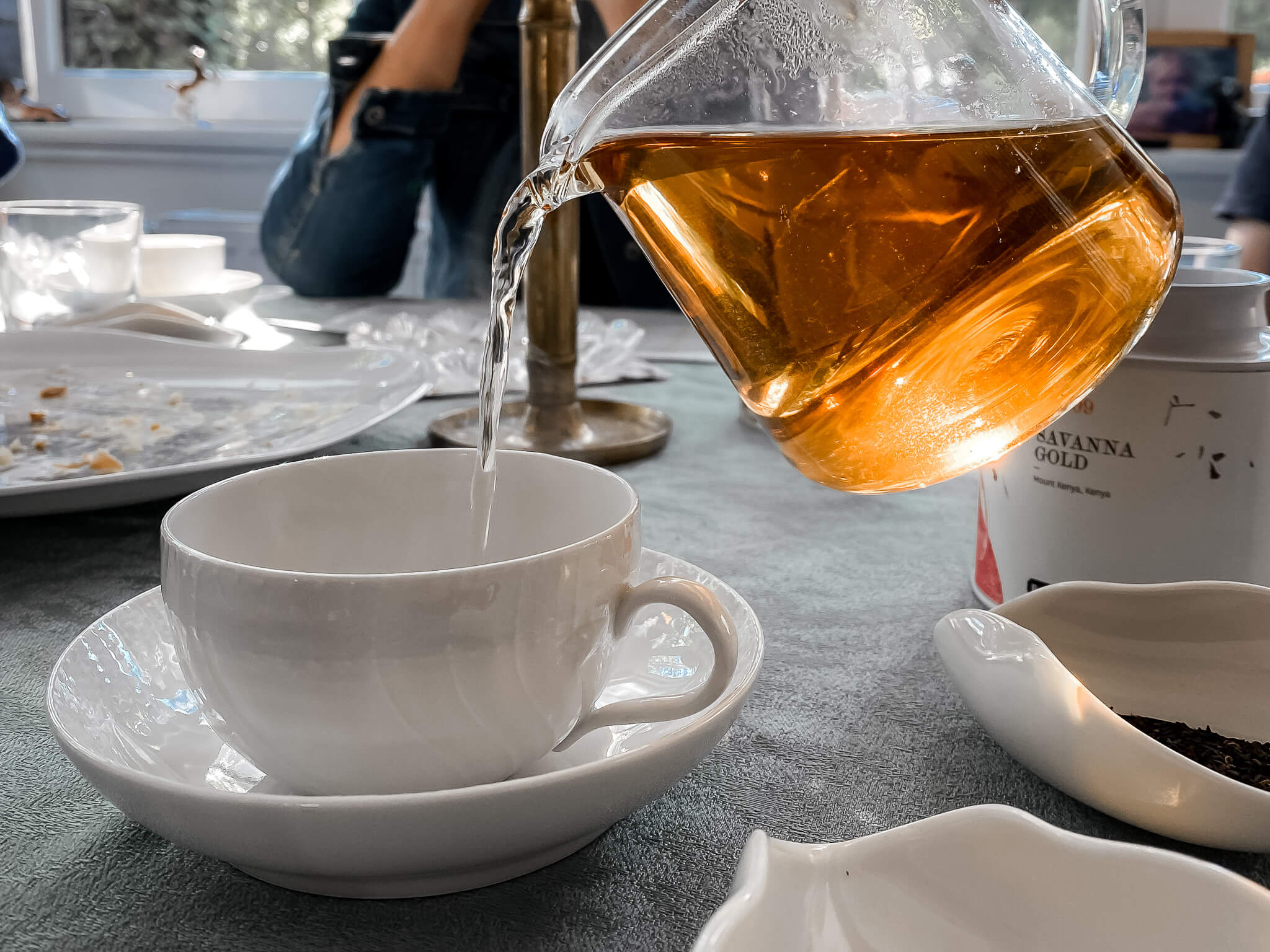 Tee wird aus einer Glaskanne in eine Tasse eingegossen