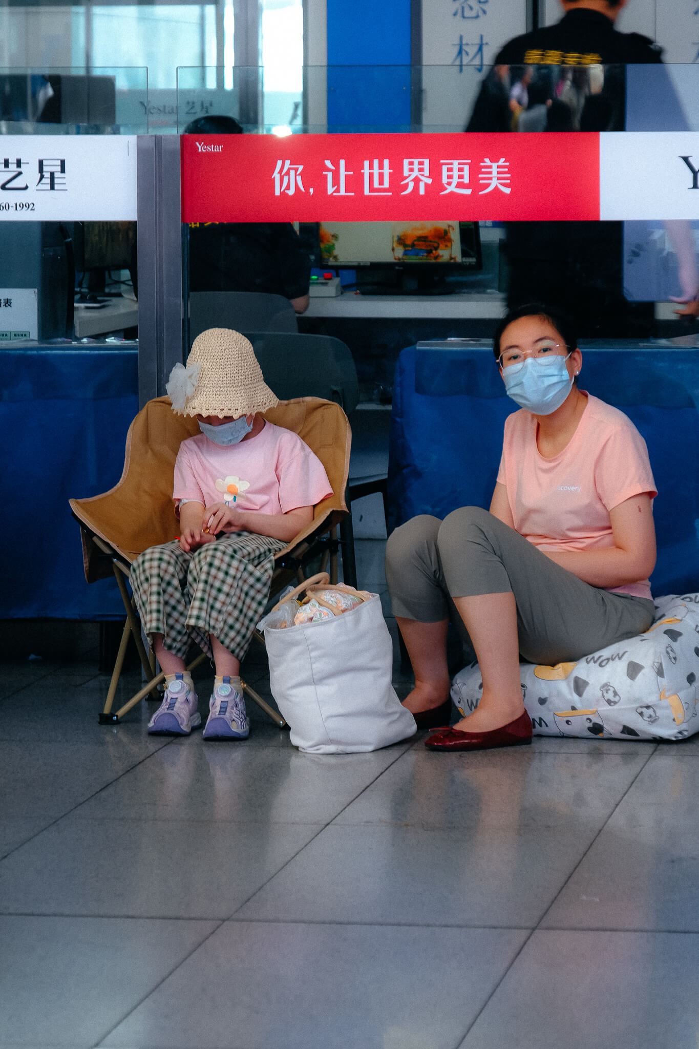 Wartende Frau mit Kind auf Campingsessel im Bahnhof von Beijing