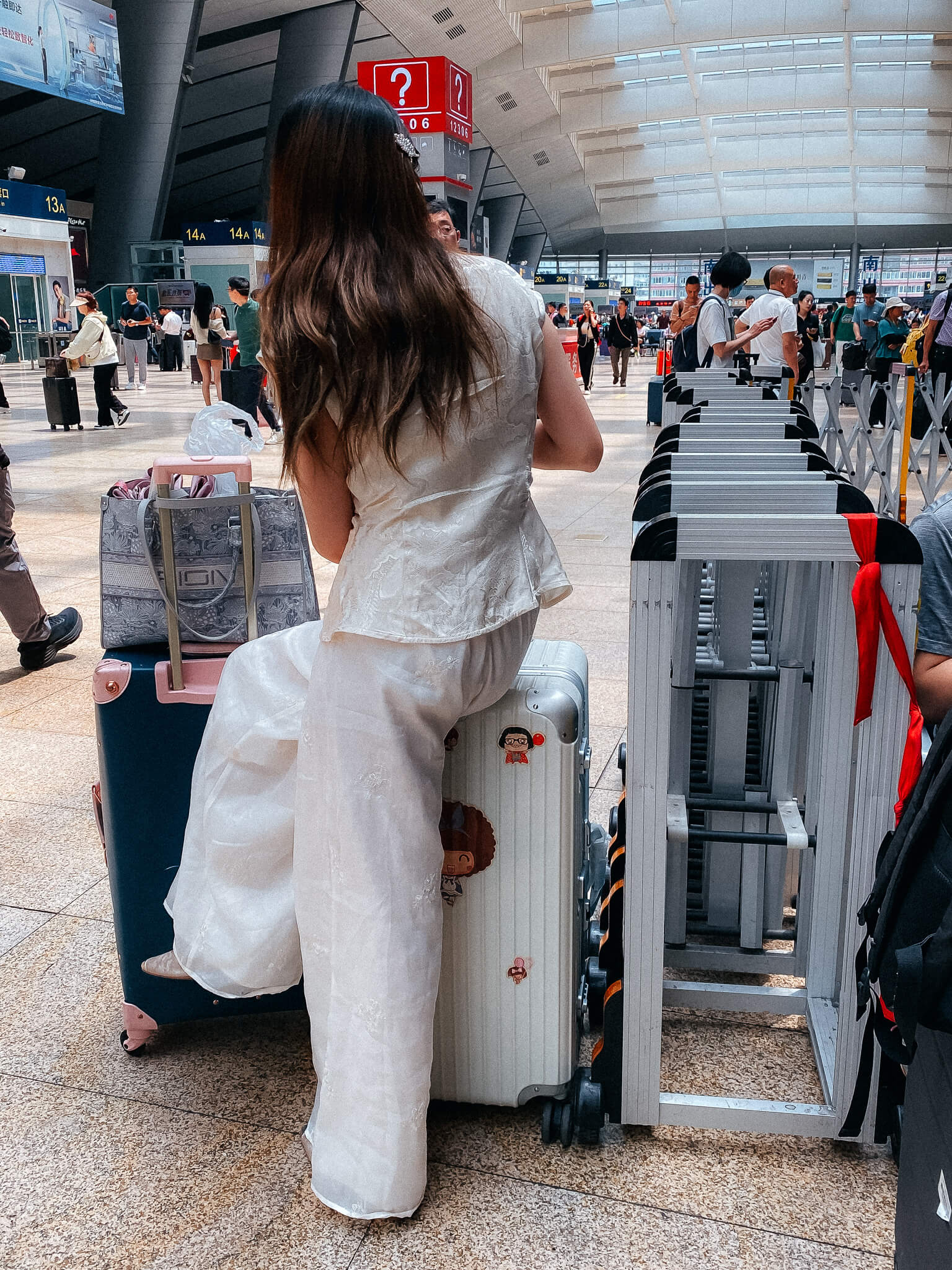 Wartende Frau auf Rollkoffer im Südbahnhof in Beijing