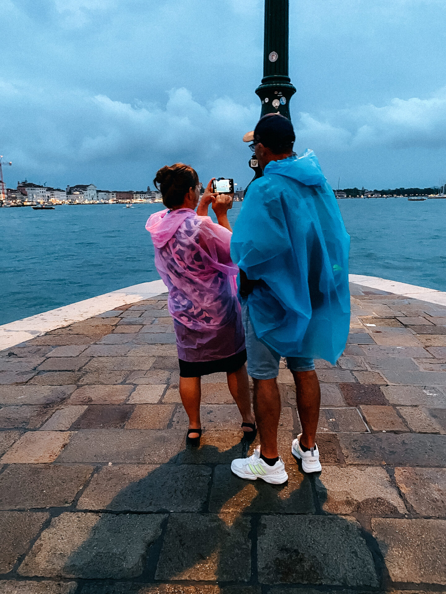 Touristen in Regenponchos an der Punta della Dogana in Venedig