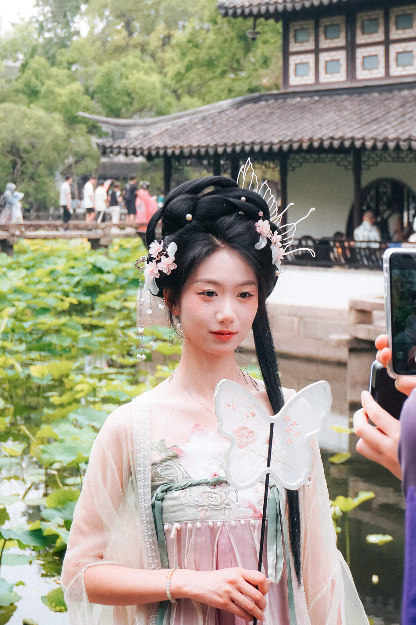 China, Suzhou, Garten: jung Frauen in traditionellem Hanfu-Gewand mit aufwendiger Frisur wied fotografiert 