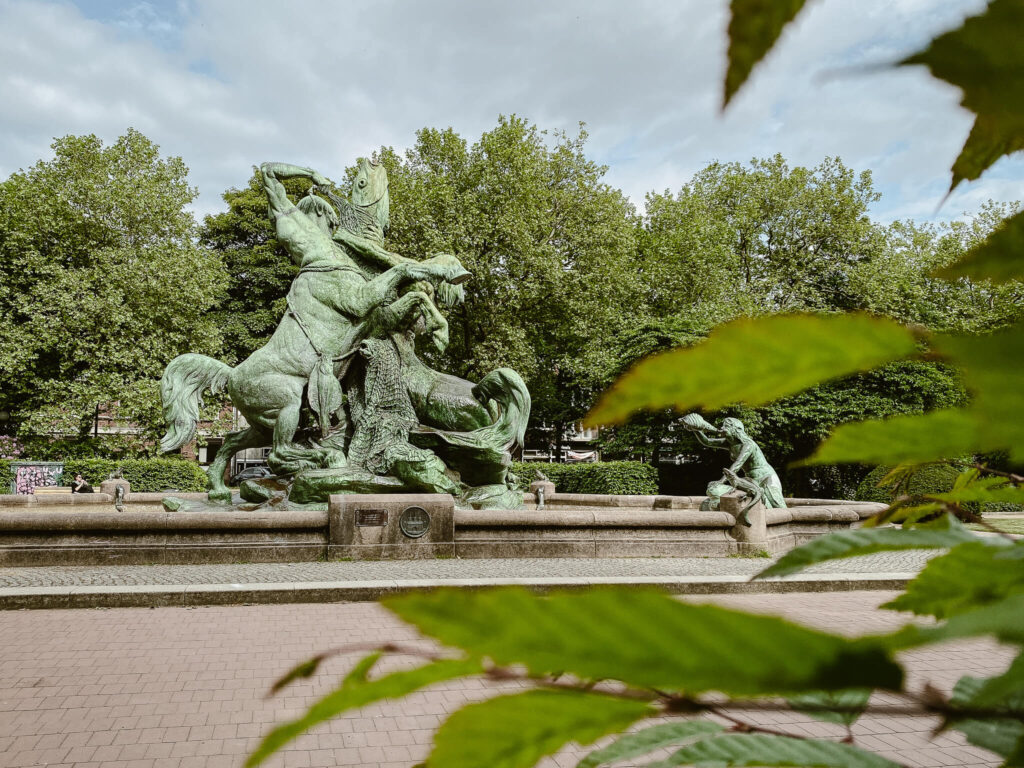 Blick durch Blätter auf den Stuhlmann-Brunnen