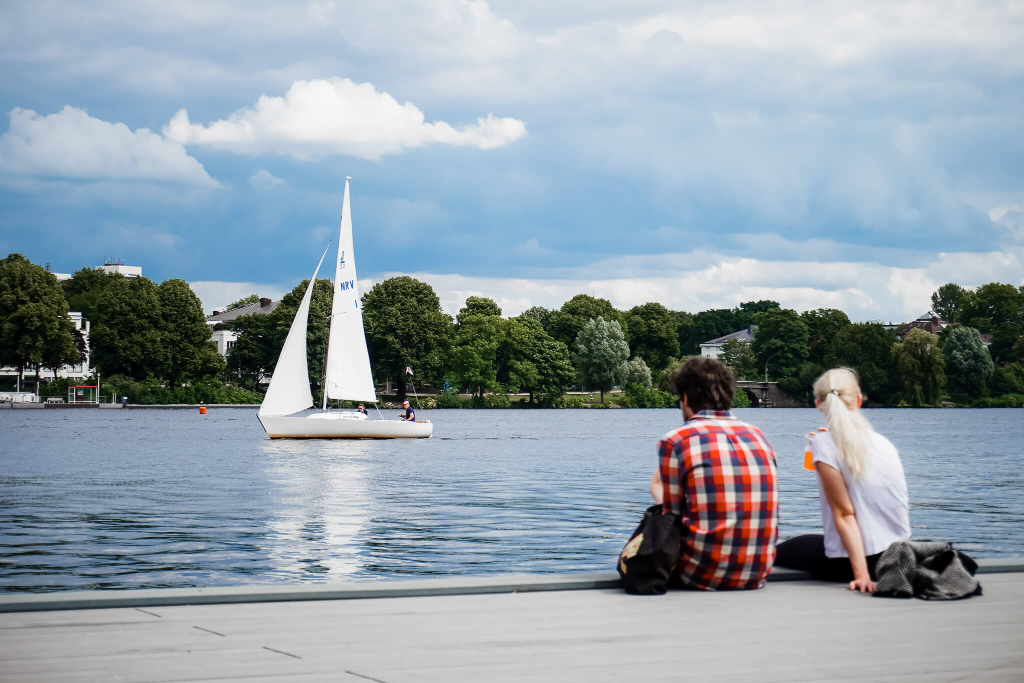 Ein Paar sieht ein Segelboot auf der Alster