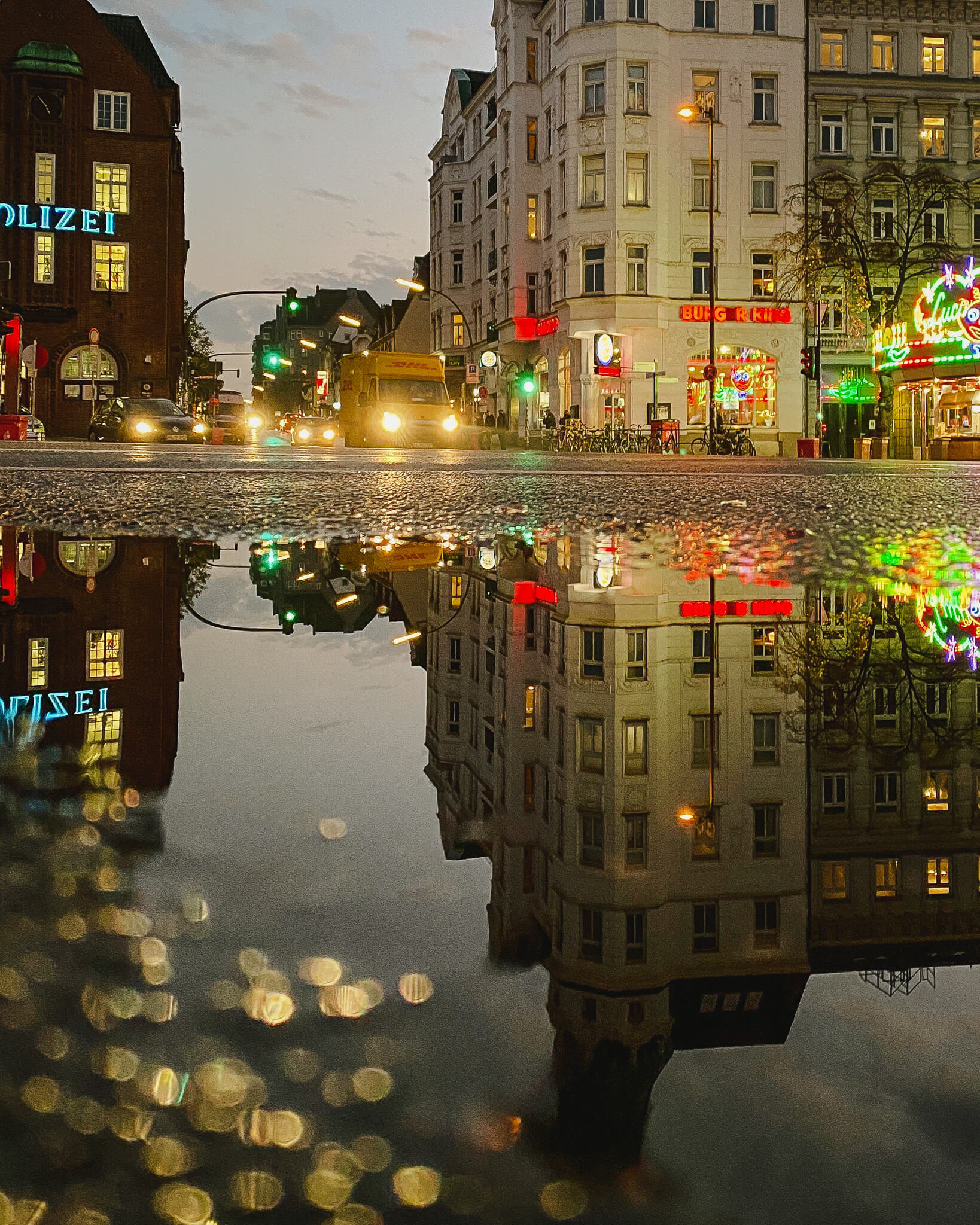 Lichter spiegeln sich in Pfützen auf der Reeperbahn