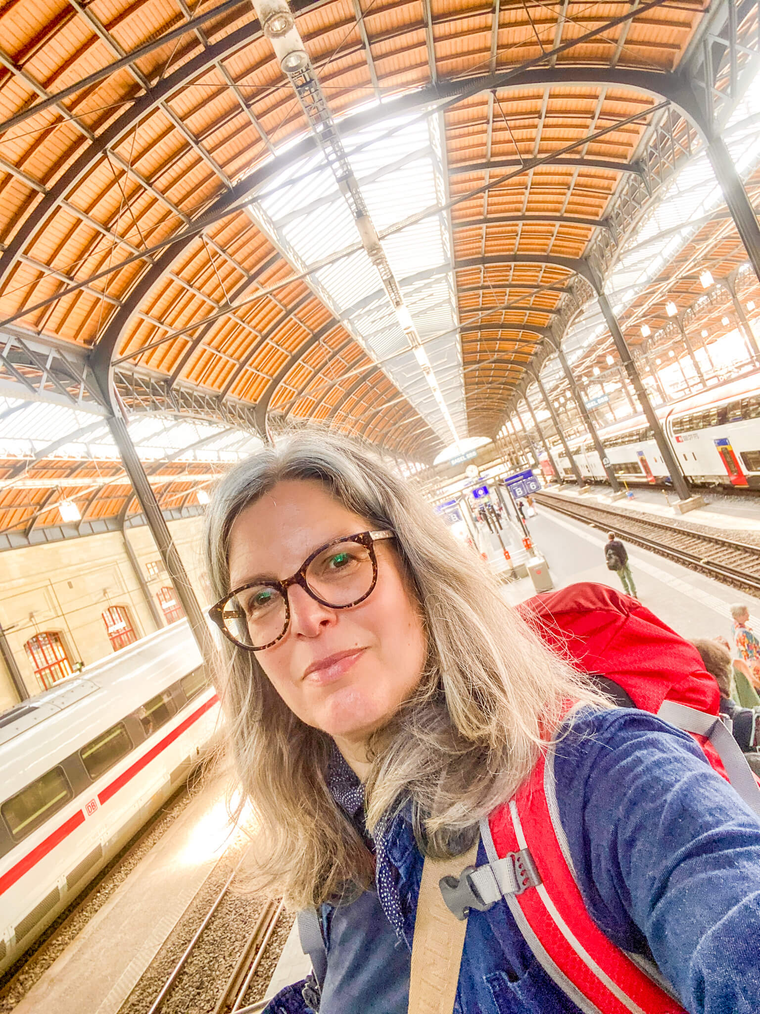 Selfie von Kirsten Rick mit Rucksack auf einem Bahnhof